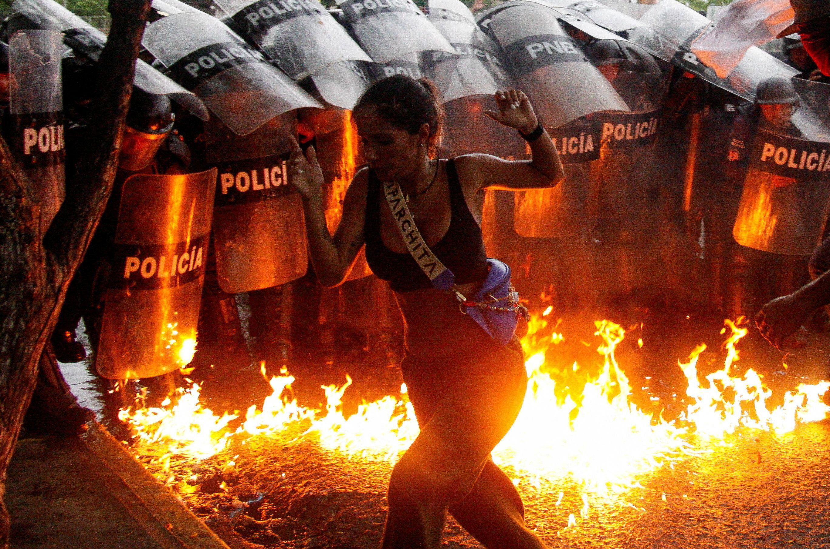 Rat protiv droge ili promena režima - šta je Trampov cilj u Venecueli 3 A woman runs in front of riot police, with flames on the road, during a protest in Venezuela in July, following Nicolas Maduro claiming victory in the presidential election.