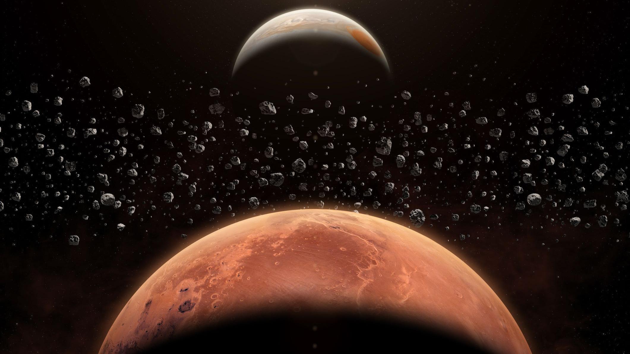 Ilustracija prikazuje pojas asteroida koji kruže oko našeg Sunca između Marsa, crvene boje u prvom planu, i Jupitera u daljini