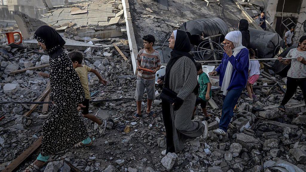 Žene i deca hodaju po ruševinama u Gazi