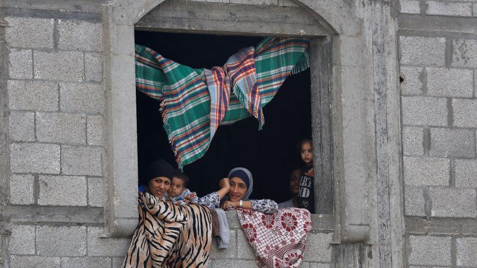 Kako je Tramp postigao dogovor za Gazu, koji je uporno izmicao Bajdenu 5 žene i deca gledaju kroz prozor kamene zgrade