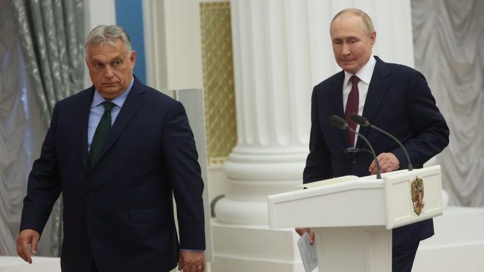 Kako će Putin u Budimpeštu: Može li 'Leteći Kremlj' proći kroz EU 2 Dvojica muškaraca u odelima prolaze pored govornice, obojica deluju zabrinuto