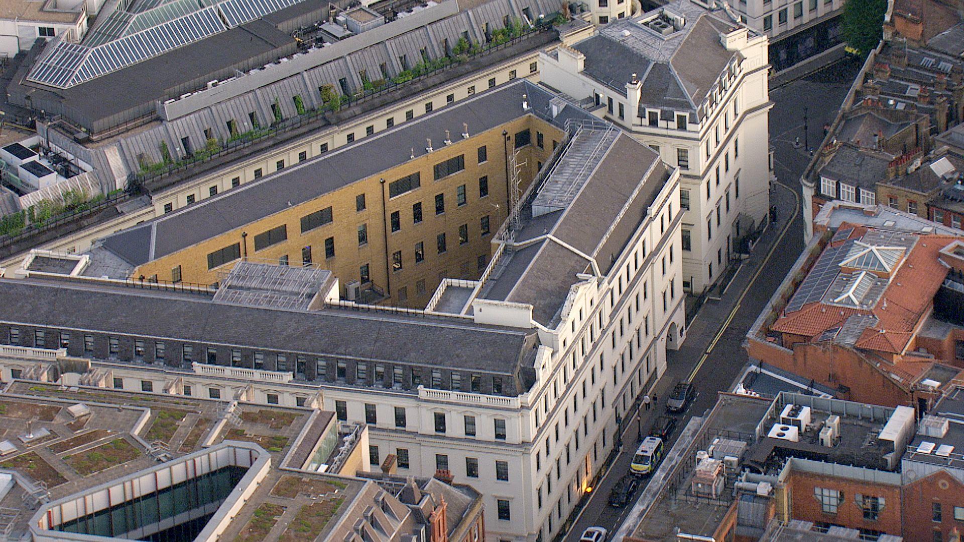 A view from a helicopter of Charing Cross police station, a white, late-Georgian stucco-fronted building forming a triangular shape, with the outline of the courtyard visible in the middle