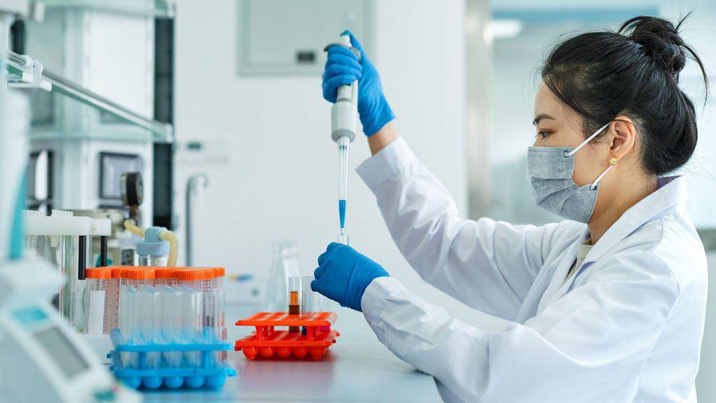 Nova nada: Ove vakcine bi mogle da zaustave rak dojke 3 Fotografija naučnice u laboratoriji. Ima tamnu kosu podignutu u punđu i nosi beli mantil, gumene rukavice i zaštitnu masku. Pomoću igle ubrizgava tečnost u epruvete.