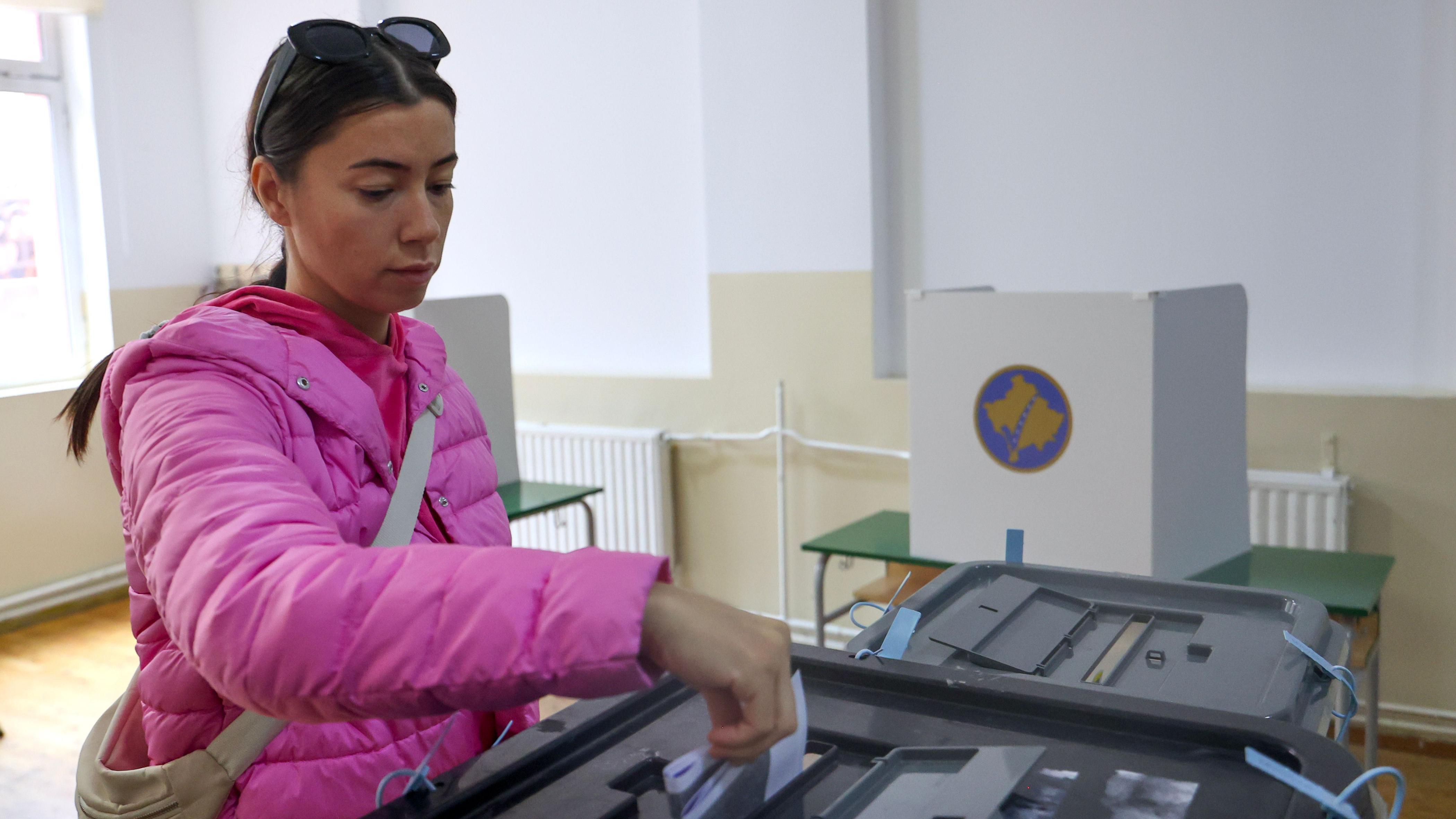 Tamnokosa devojka u roze zimskoj jakni sa smeđom torbom preko ramena glasa na izborima na Kosovu