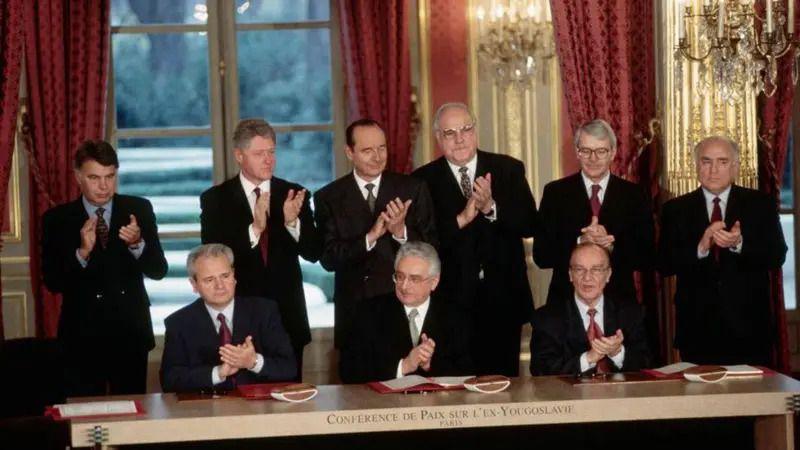 Milošević, Tuđman i Izetbegović sede ispred primeraka sveže potpisanog Dejtonskog mirovnog sporazuma u ​​Jelisejskoj palati 14. decembra 1995, u prisustvu šest svetskih lidera
