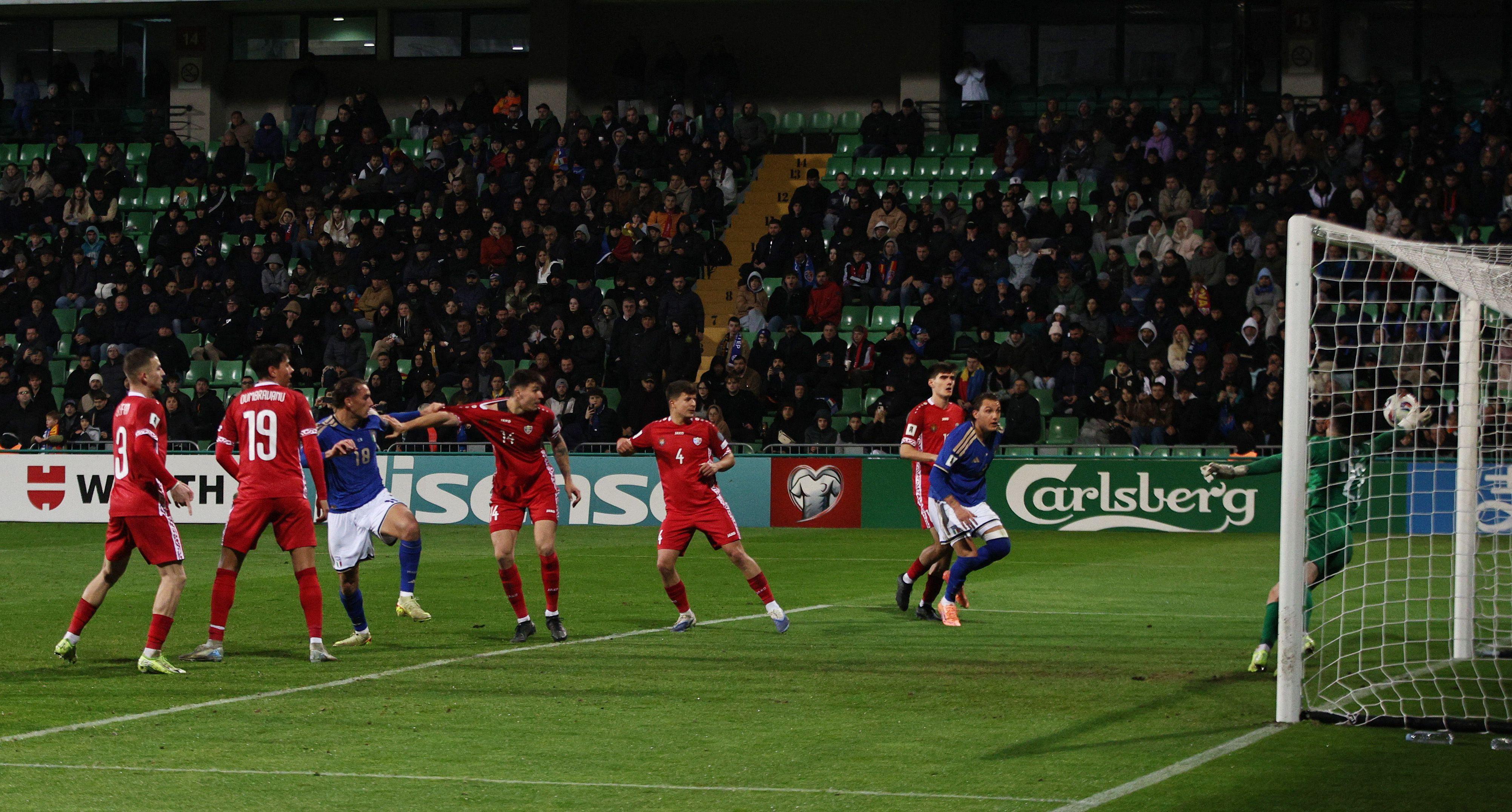 Igrači Italije i Moldavije gledaju u loptu koja završava u golu moldavske reprezentacije