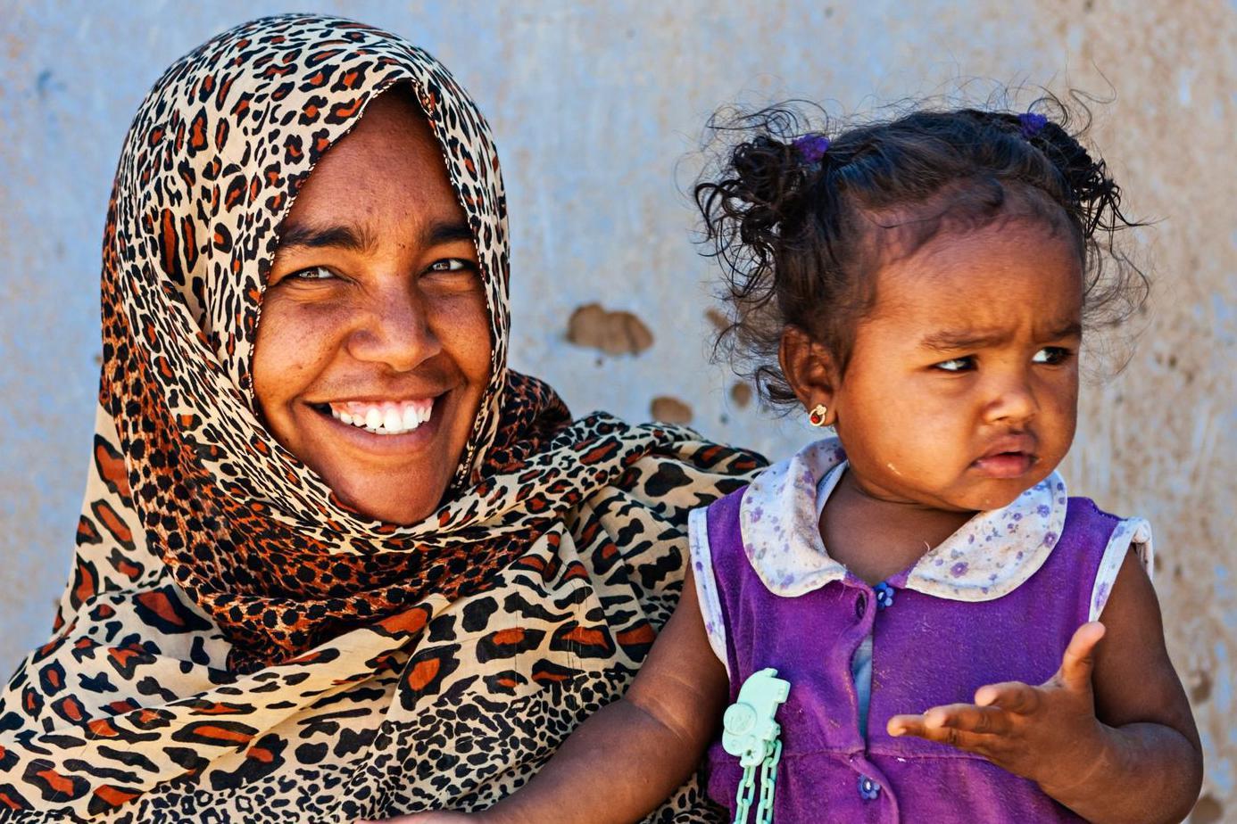 Severnoafrikanka se osehuje dok u rukama drži dete obučeno u roze haljinicu 