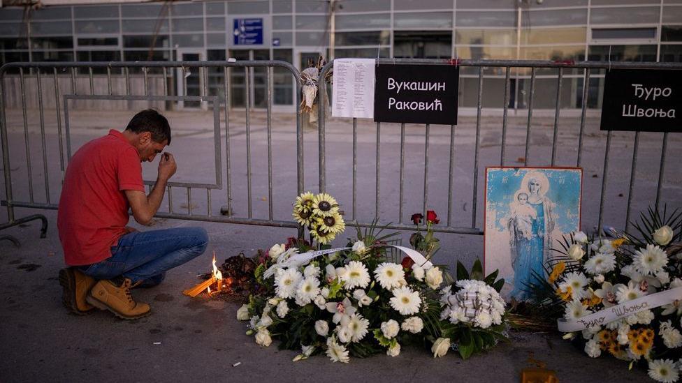 Čovek se krsti ispred Železničke stanice u Novom Sadu gde je položeno cveće