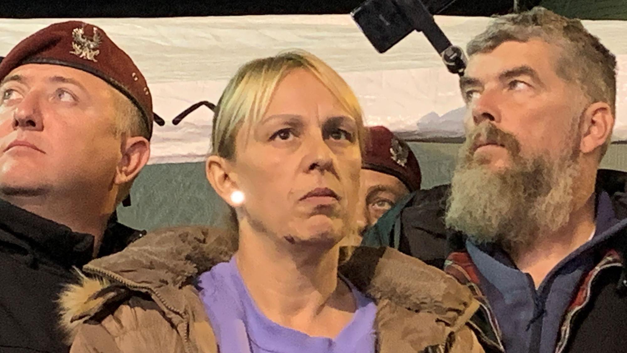 Dijana Hrka okružena dvojicom muškaraca, jedan ima crvenu beretku a drugi sedu, dugu bradu