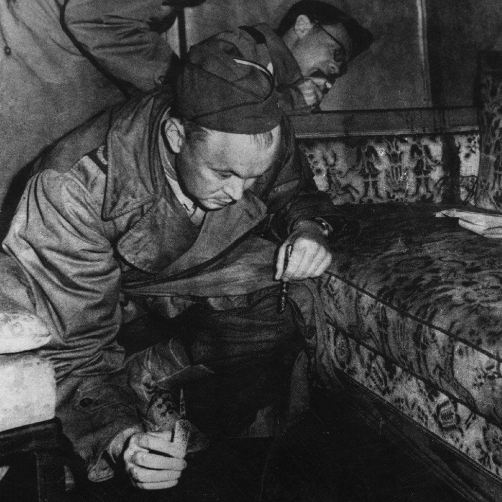 Saveznički ratni novinari ispituju sofu u Hitlerovom bunkeru 1945. godine - kaže se da je mrlja na naslonu fotelje krv.
