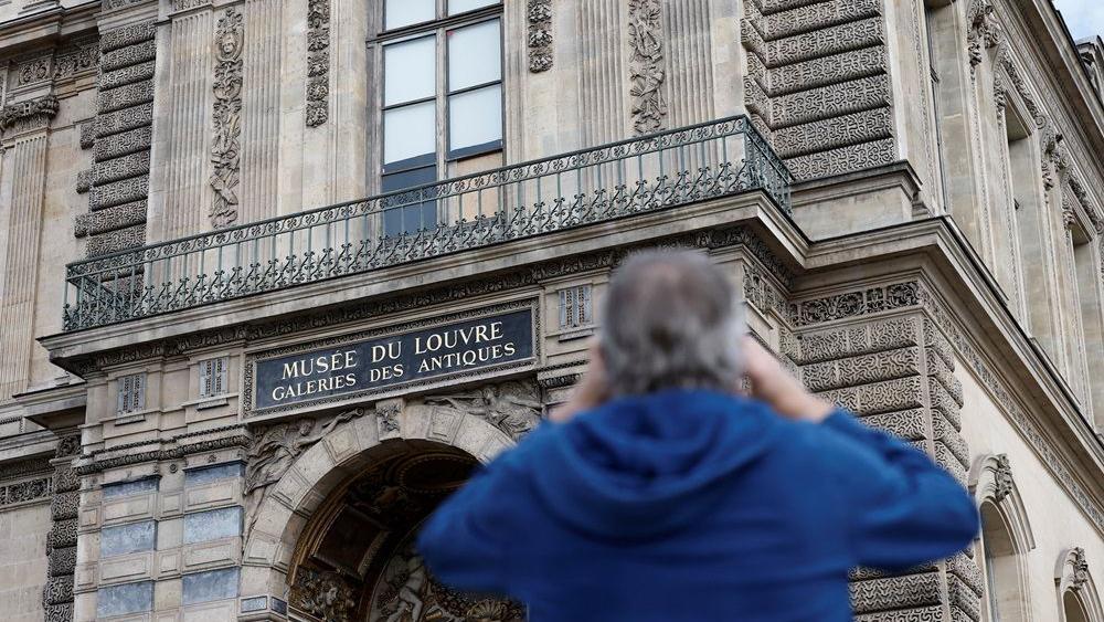 Čovek fotografiše razbijeni prozor zaštićen drvenom pločom u muzeju Luvr posle pljačke nakita, pljačka u luvru, krađa u luvru, opljačkan luvr, opljačkan muzej luvr