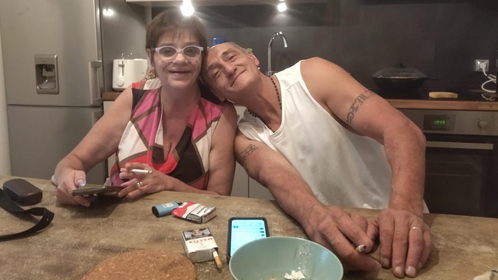 Andrea i Aleho sede u kuhinji. Svako drži upaljenu cigaretu, a ona mobilni telefon. Na pultu se nalaze još jedan telefon, dve kutije cigareta, činija koja služi kao pepeljara i dve futrole za naočare. Aleho naslanja glavu na Andreino rame dok gledaju u kameru.