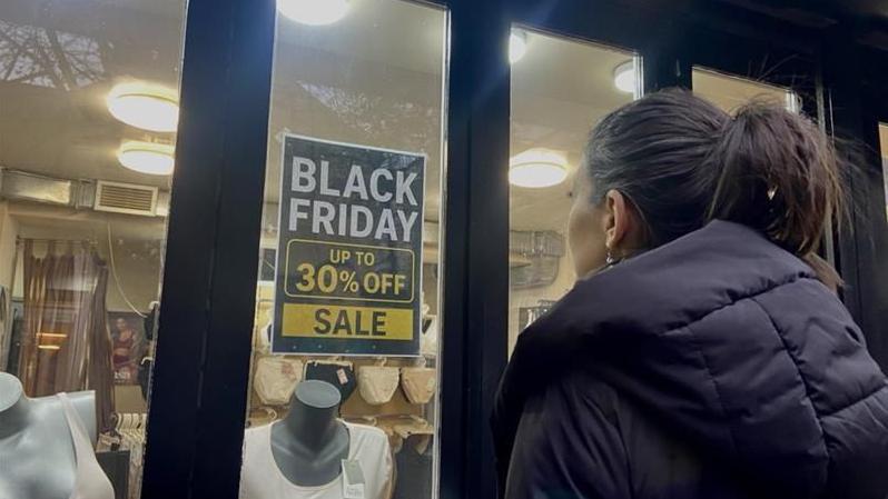 devojka gleda u izlog na kojem piše sniženje, kupovina, šoping, žene u kupovini