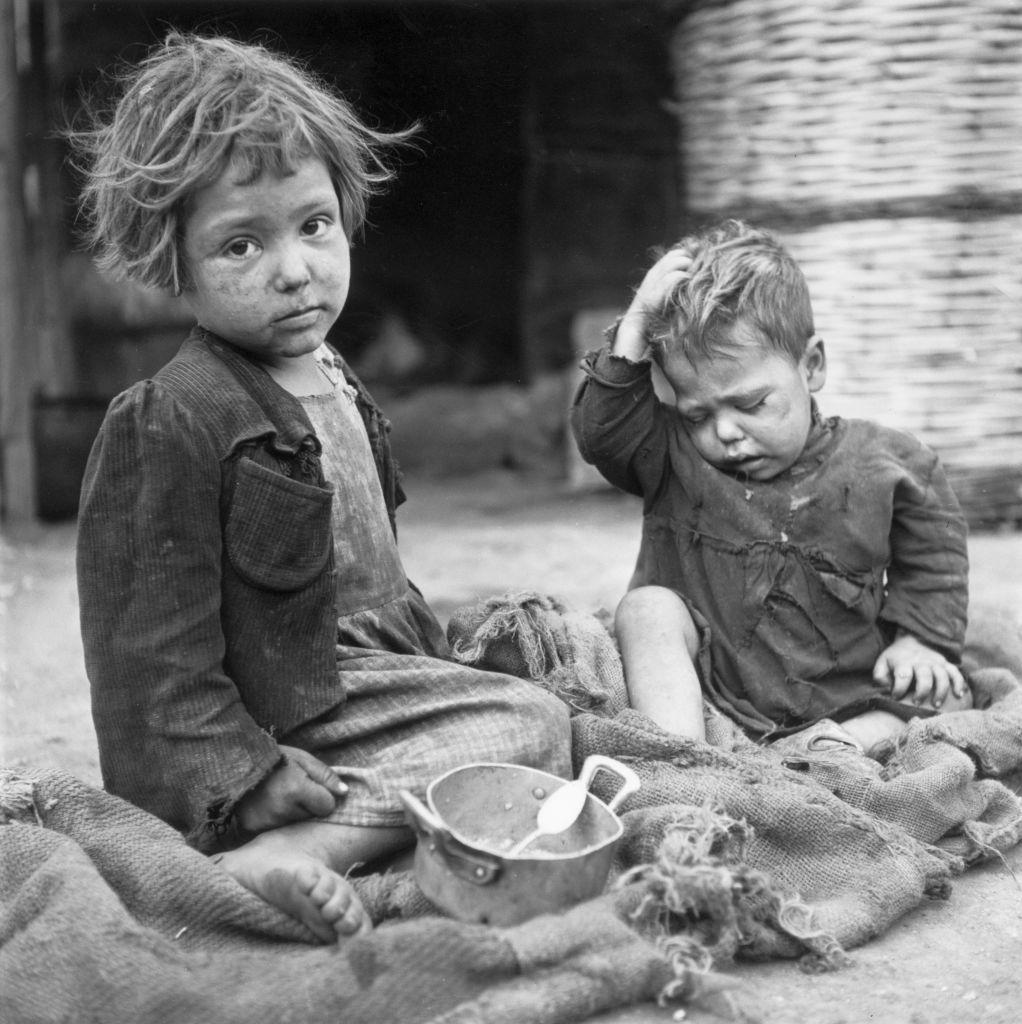 Od gladi do nade: 'Voz sreće' koji je doneo novi život za 70.000 italijanske dece 3 Crno bela fotografija dece kako sede na podu, ispred njih prazna šerpica