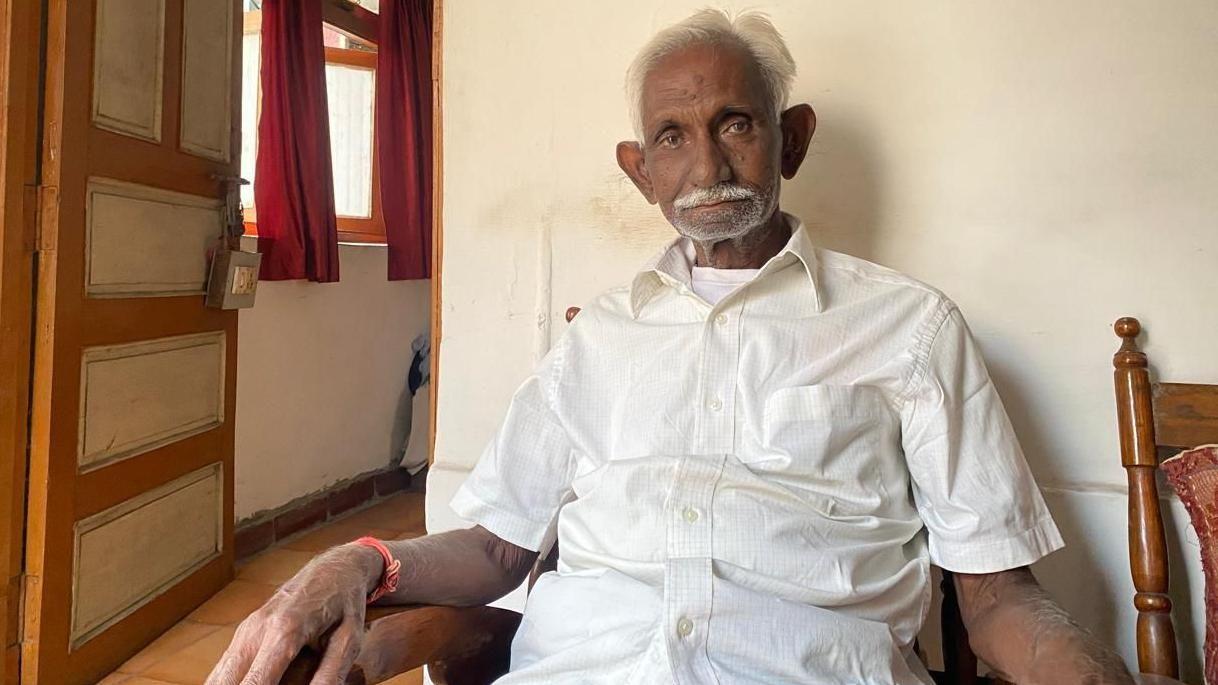 Optužba za mito od osam dolara mu uništila život - proglašen nevinim posle 39 godina 1 Džagešvar Prasad Avadija, stariji Indijac, sedi na drvenoj stolici. Nosi belu košulju i belu majicu. Ima sedu kosu i sede brkove.