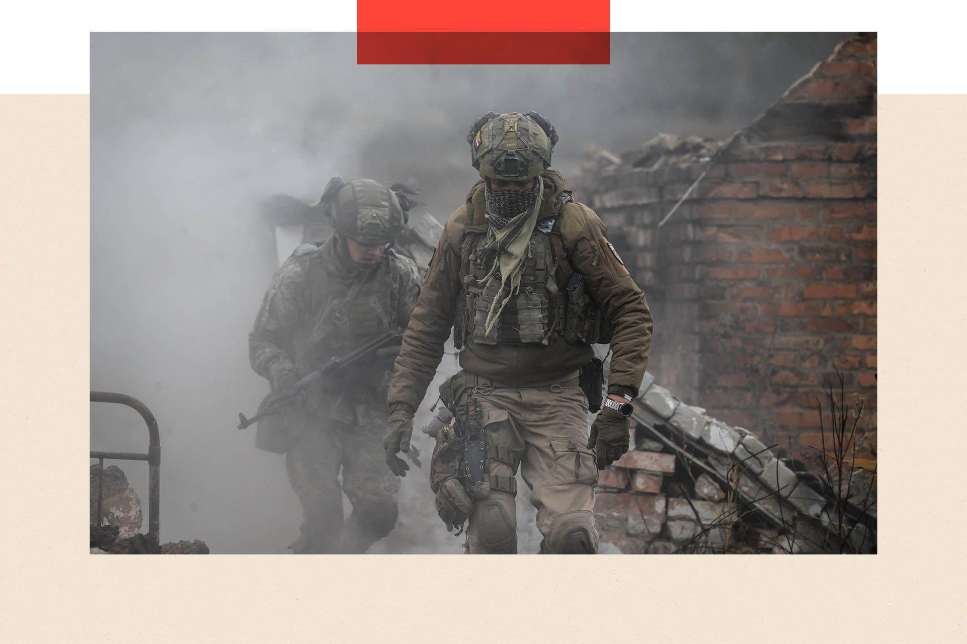 Dva vojnika u punoj opremi, iza njih su ruševine