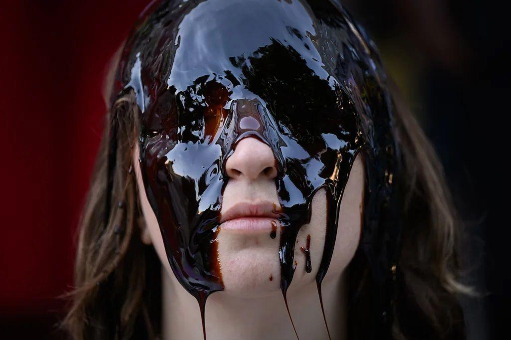 devojka stoji a oči su joj premazane tamnim uljem, protest zbog nafte, ekološki protest