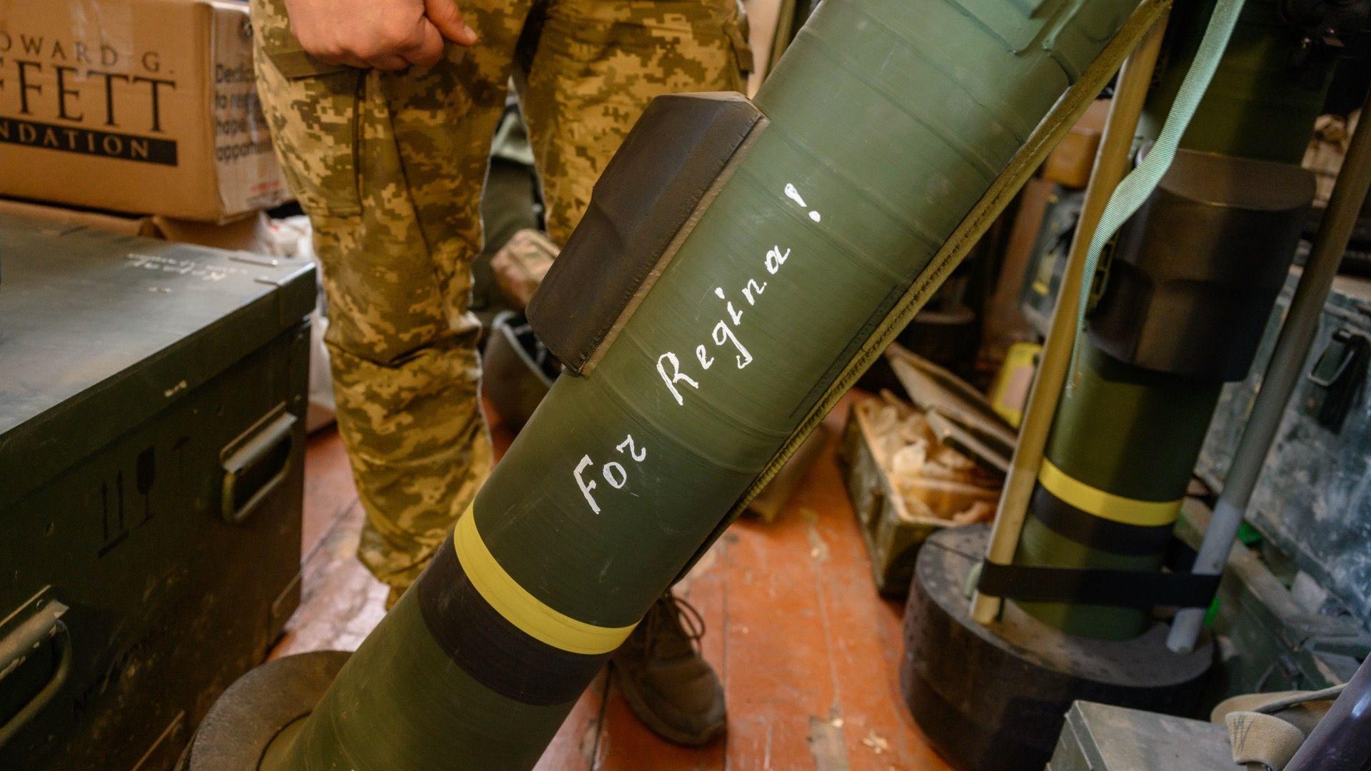 Zamrznuta ruska imovina: Šta hoće EU i zašto se Belgija protivi 7 Zelena raketa sa natpisom „Za Reginu!“ belom bojom. Raketa je na postolju na podu unutar sobe, a iza nje su noge vojnika u kamuflažnim pantalonama.