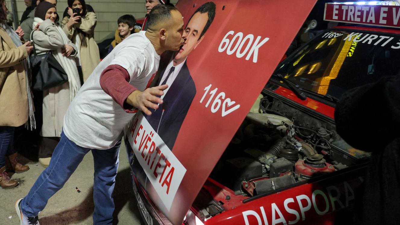 Izbori na Kosovu: 'Politički zemljotres', kriza opozicije i Kurtijev (verovatni) treći mandat 1 Muškarac ljubi Kurtijev poster zalepljen na haubi automobila