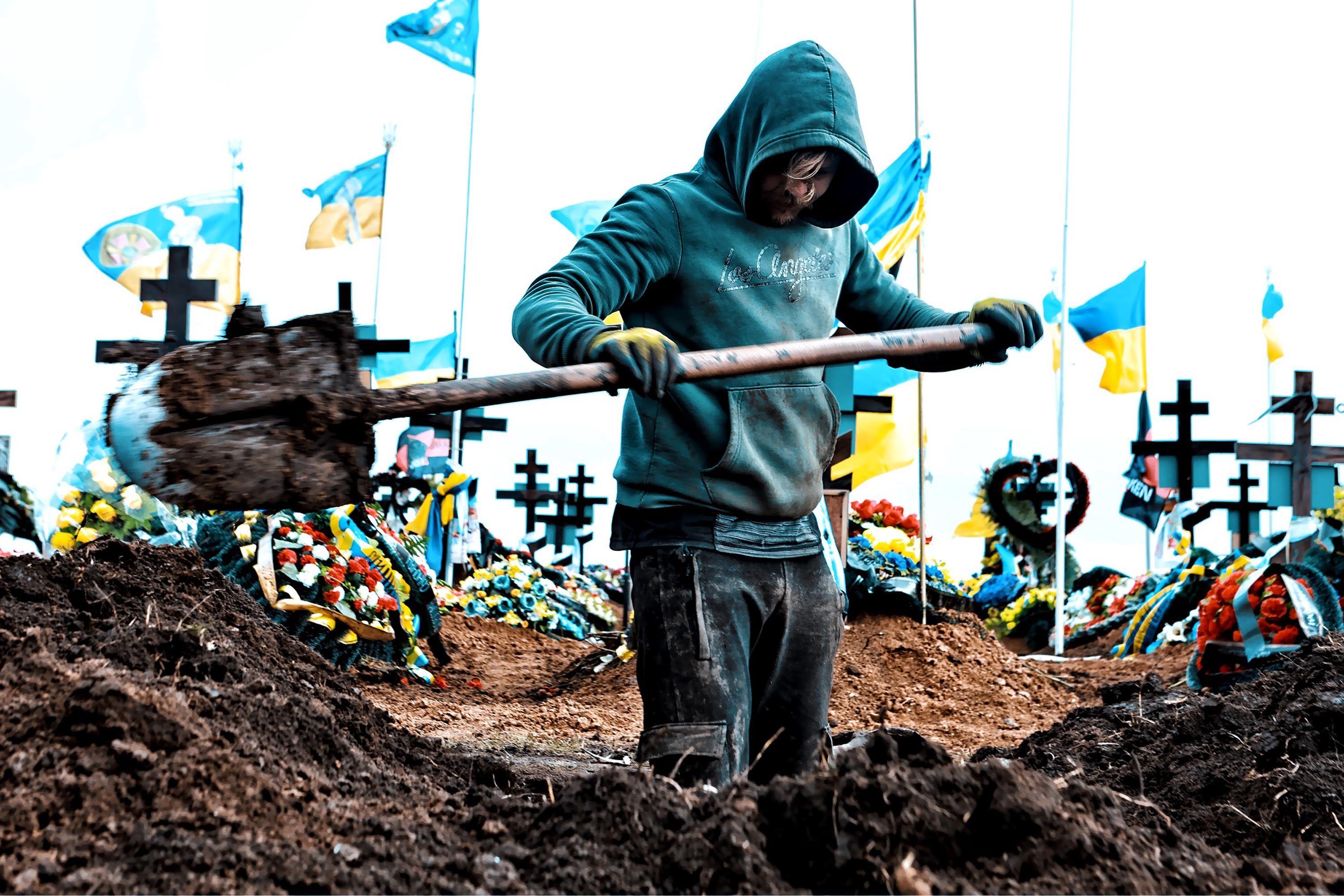 Zamrznuta ruska imovina: Šta hoće EU i zašto se Belgija protivi 2 Muškarac kopa grob na groblju u Odesi 16. marta 2024. Oko deset ukrajinskih zastava vijori se na belim jarbolima iza njih. Kopač groba u nosi tirkiznu duksericu sa kapuljačom, u rukama mu je lopata