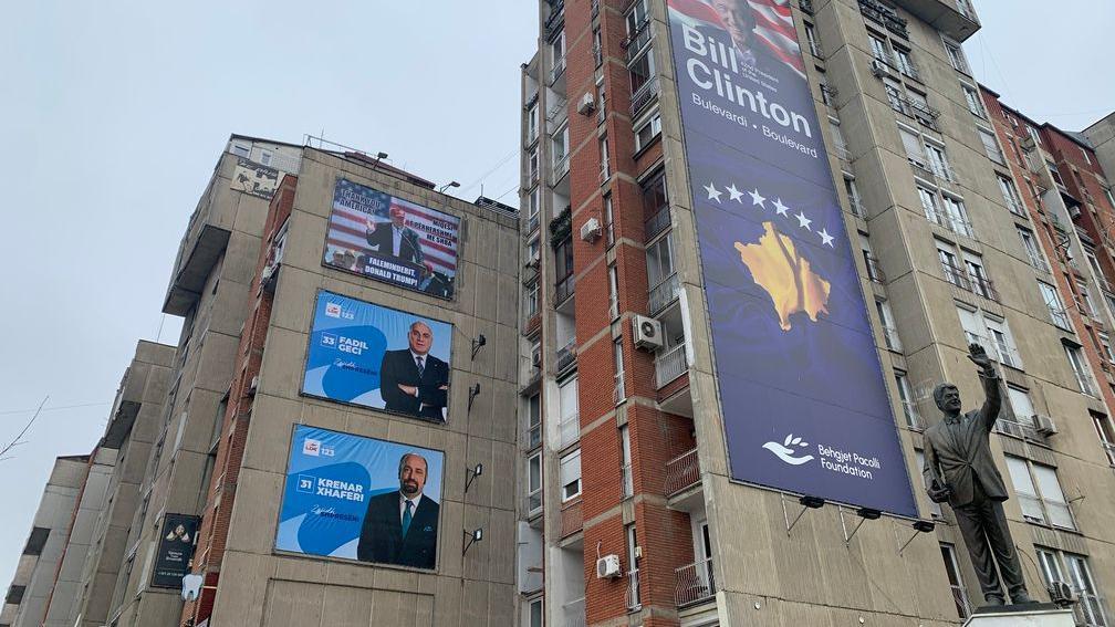 Dva predizborna postera iznad kojih je Donald Tramp, a na zgradi pored je bilbord posvećen Bilu Klintonu, bišvem američkom predsedniku, gde je postavljena i njegova statuta