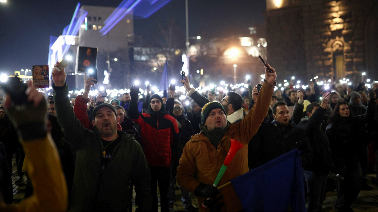 Ljudi na protestu sa EU zastavama u jaknama i kapama po noći