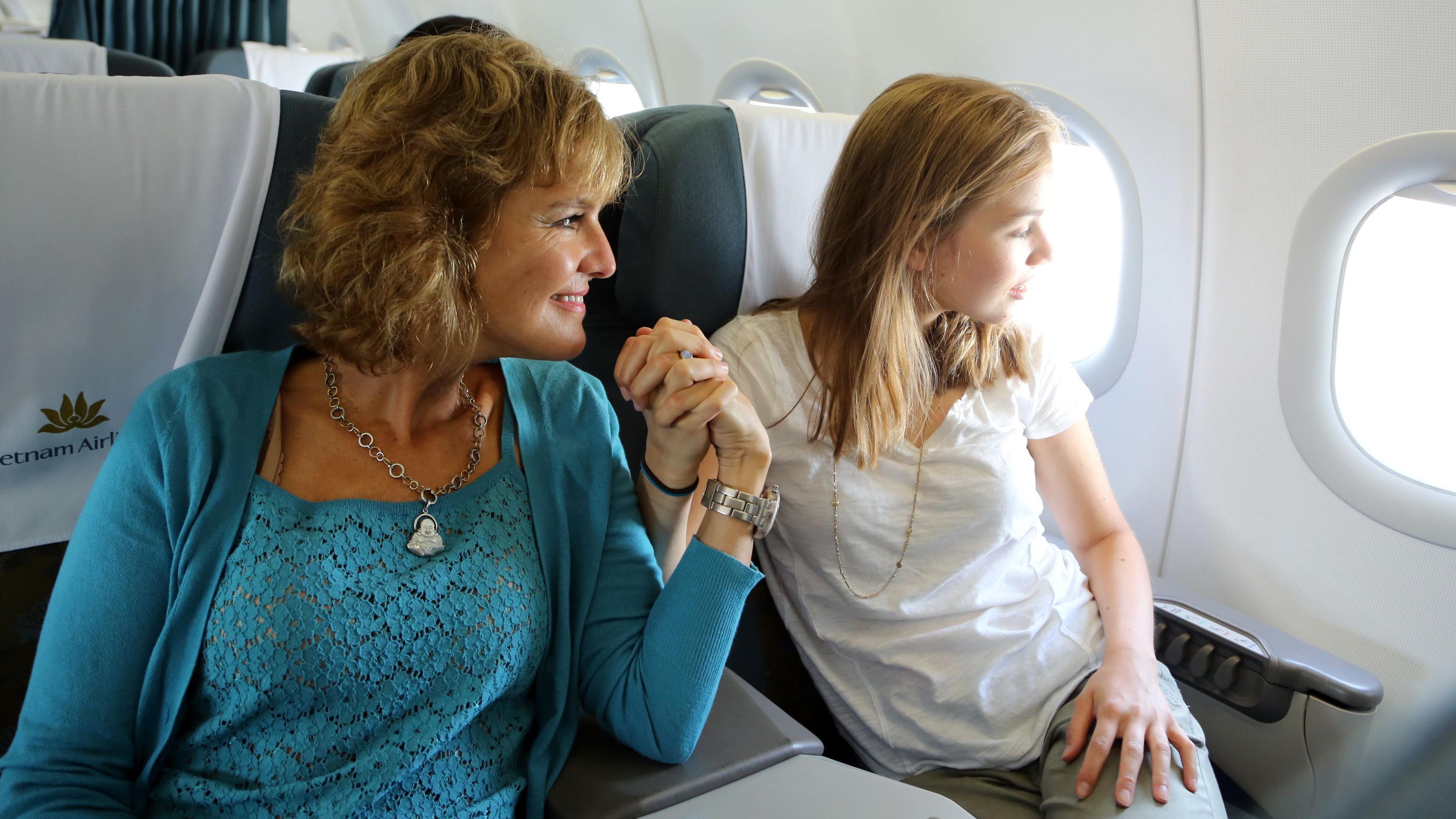 Anet i njena kćerka sede u avionu i drže se za ruke i gledaju kroz prozor.