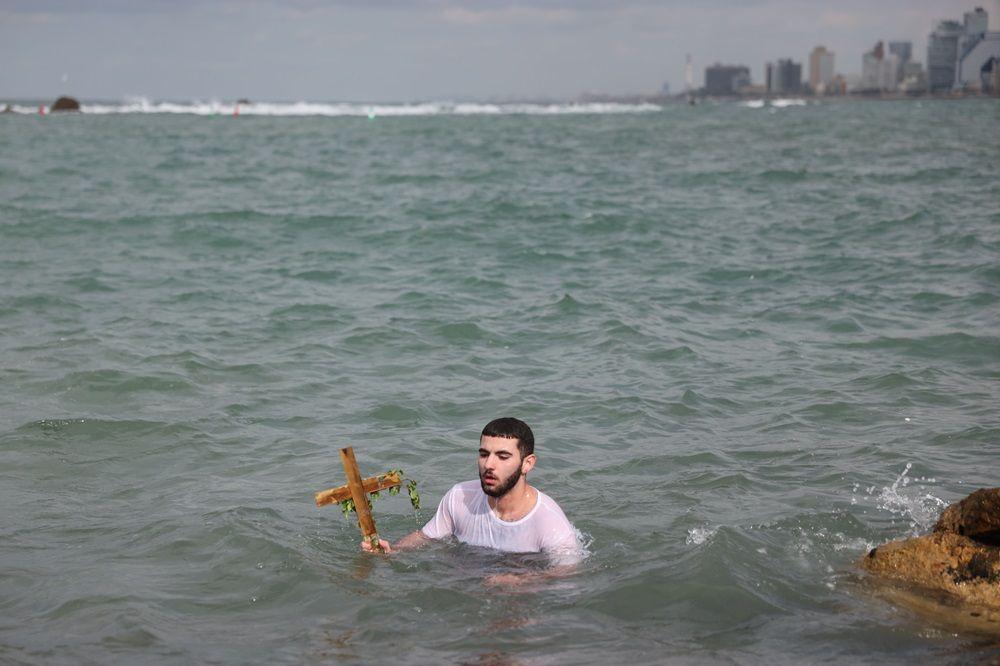 Hrišćanski vernik iz grčko-pravoslavne crkve Arhanđela Mihaila drži krst nakon što ga je izvukao iz Sredozemnog mora tokom proslave Bogojavljanja u Staroj luci Jafa u Tel Avivu, Izrael, 19. januara 2026. Godišnji festival obeležava dolazak Tri mudraca u Vitlejem da se poklone novorođenom Hristu prema hrišćanskoj tradiciji