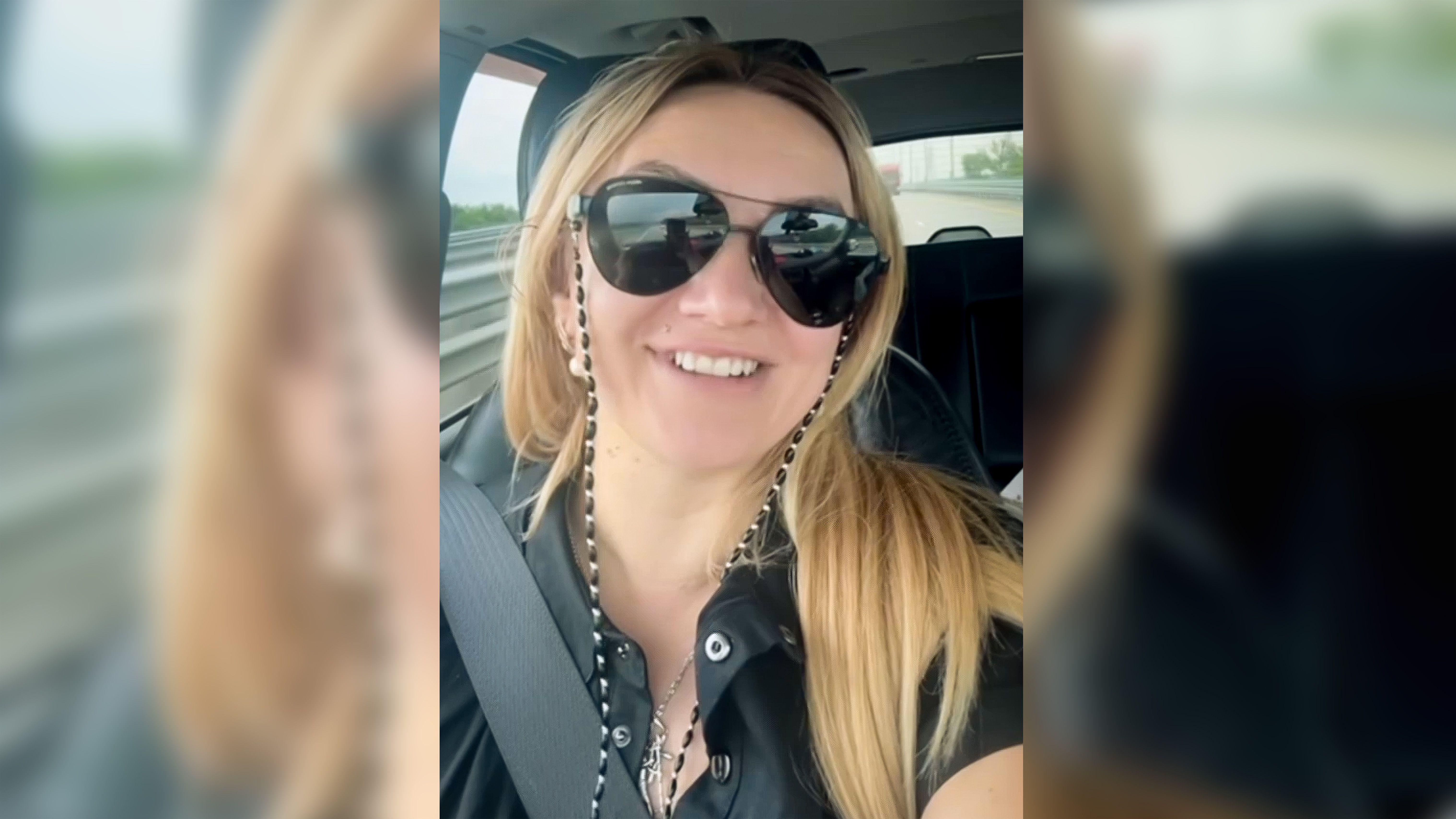 'Prevareni smo': Žena koja vrbuje strance da se bore za Rusiju 2 Polina Azarnik gleda pravo u kameru dok sedi u vozilu. Ima dugu plavu kosu, nosi velike naočare za sunce i crnu majicu i osmehuje se