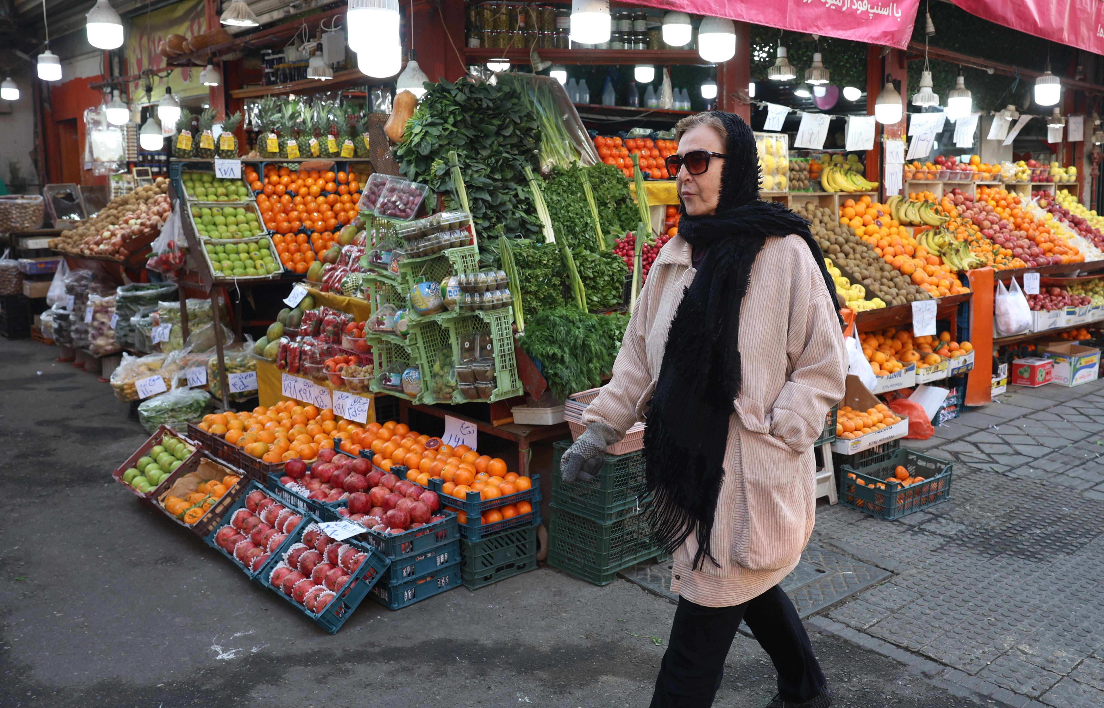 žena prolazi pored radnje sa voćem i povrćem u Teheranu