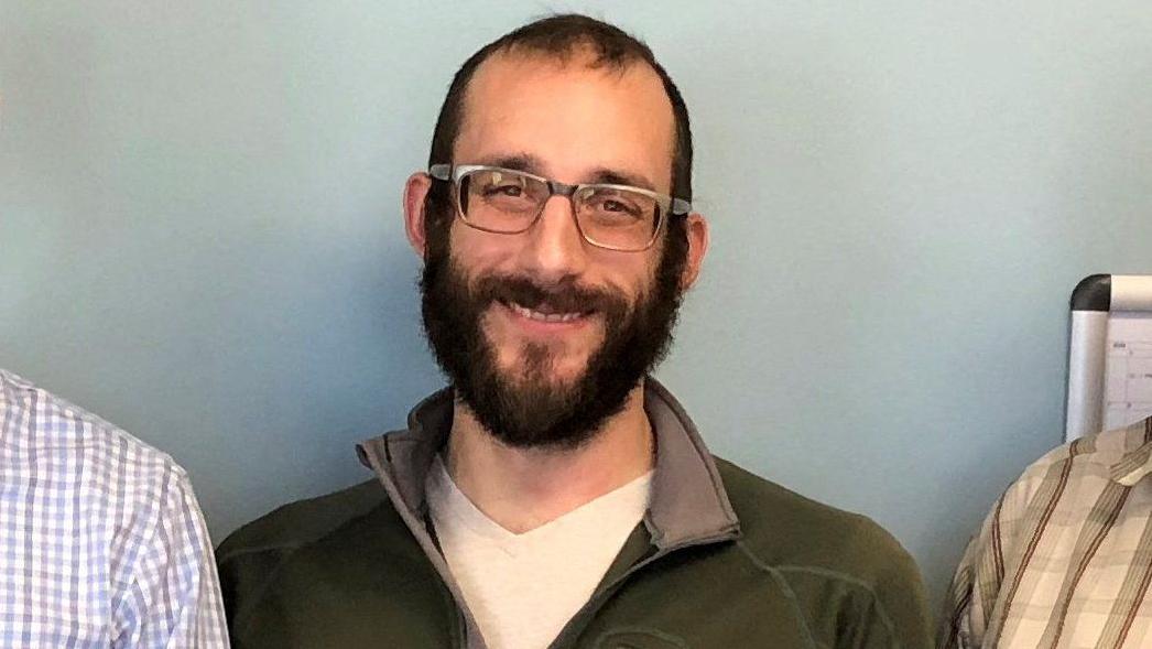 Ko je Greg Bovino, glavni izvršilac Trampove politike masovnih deportacija 4 Aleks Preti se smeši dok stoji između dvoje ljudi. Ima gustu tamnu bradu, proređenu tamnu kosu i naočare.