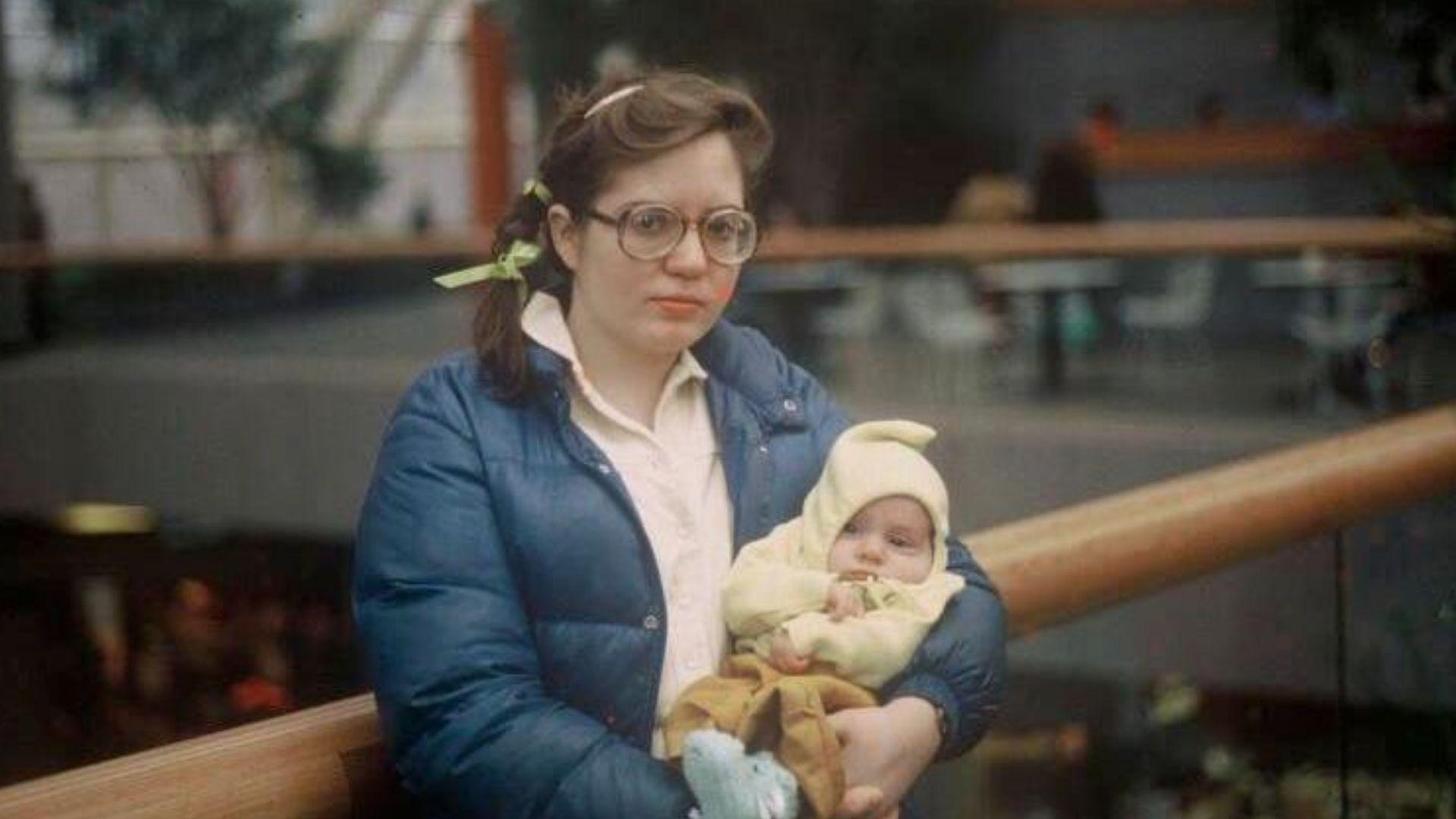 mlađa žena sedi na klupi i drži bebu u naručju
