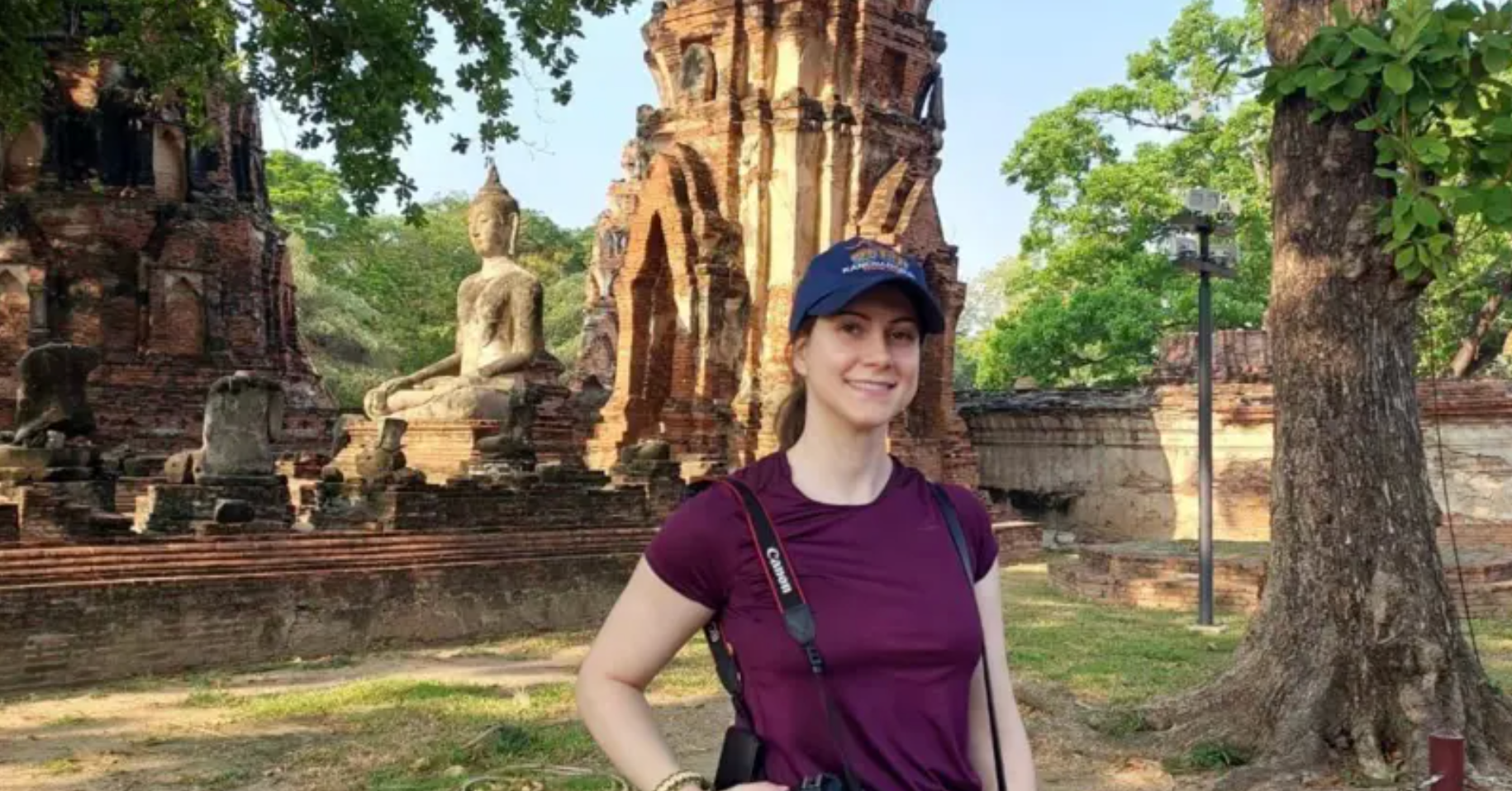 Kako su tajlandske lezbejske ljubavne priče postale višemilionska industrija 4 Devojka sa bejzbol kapom u ljubičastoj majici i fotoaparatom oko vrata ispred statue Bude na Tajlandu