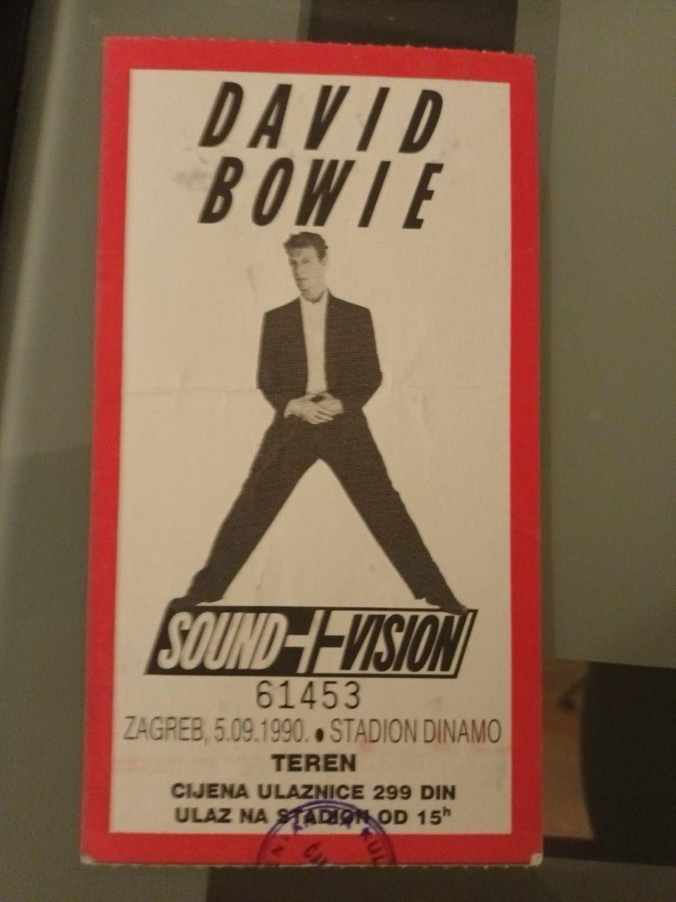 Kako se Balkan seća Dejvida Bouvija, maštovitog rokenrol buntovnika 2 Koncertna ulaznica na kojoj je Dejvid Bouvi u crnim pantalonama i sakou, ispod kojeg ima belu košulju