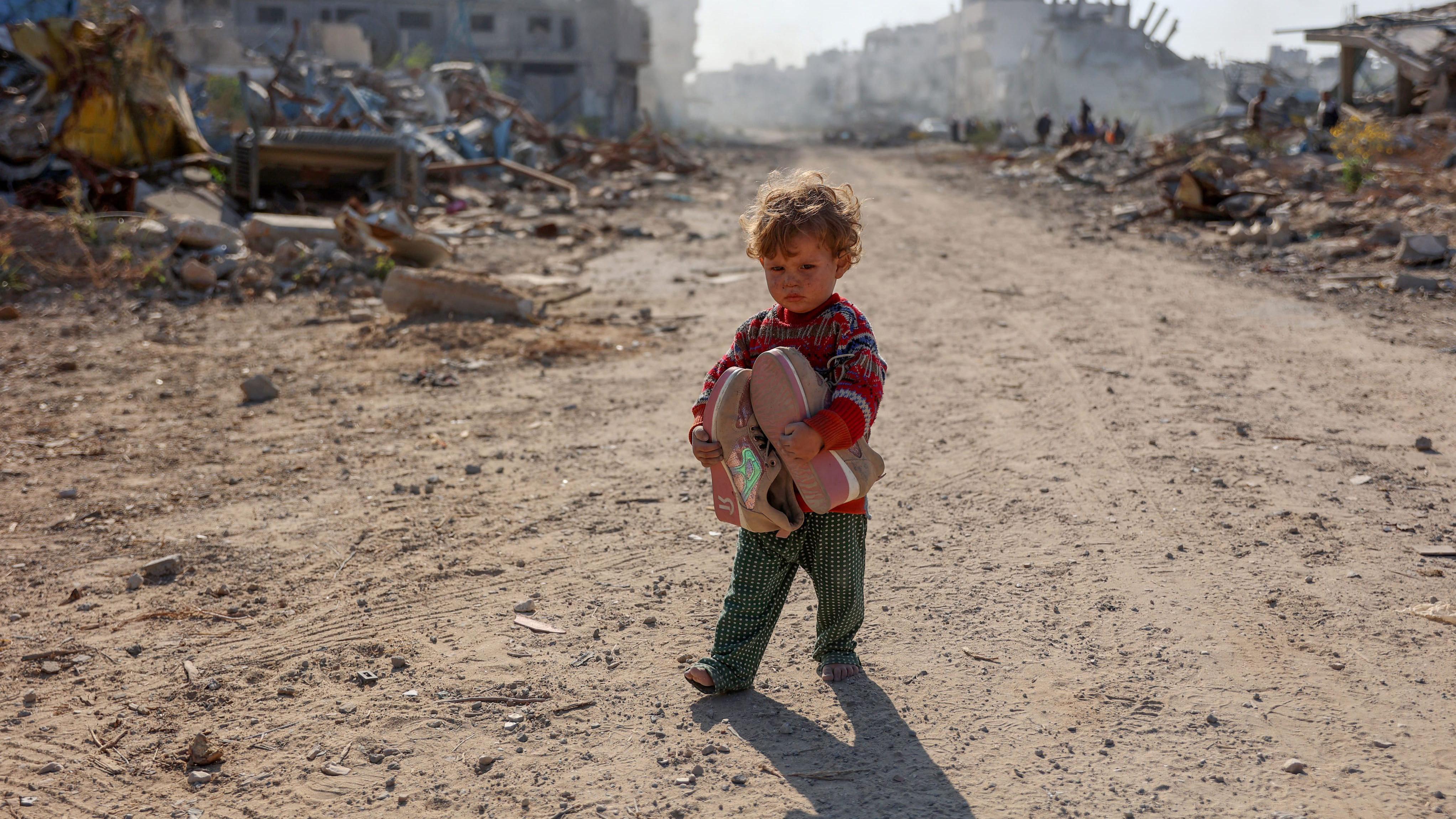 Kako odrastanje u ratu zaista utiče na jednog 11-godišnjaka 4 Palestinsko dete sa igračkama u rukama na ulici, okruženo ruševinama, u šarenom džemperu i zelenim pantalonicama