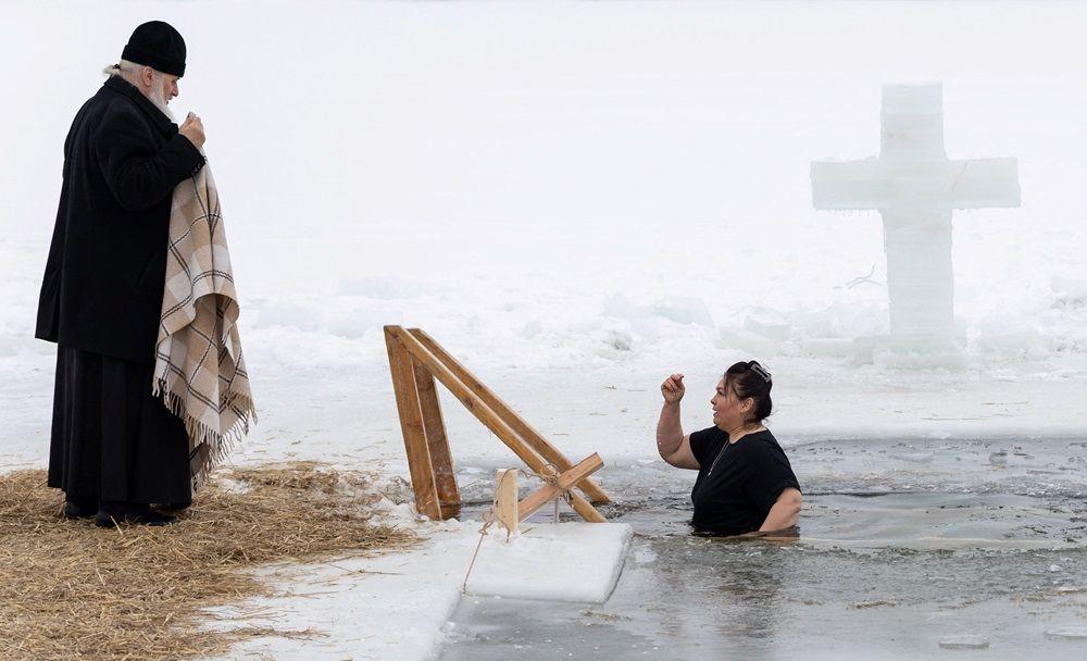 Žena izlazi iz ledene vode jezera dok sveštenik stoji u blizini tokom proslave pravoslavnog hrišćanskog praznika Bogojavljanja u gradu Stupino u Moskovskoj oblasti.