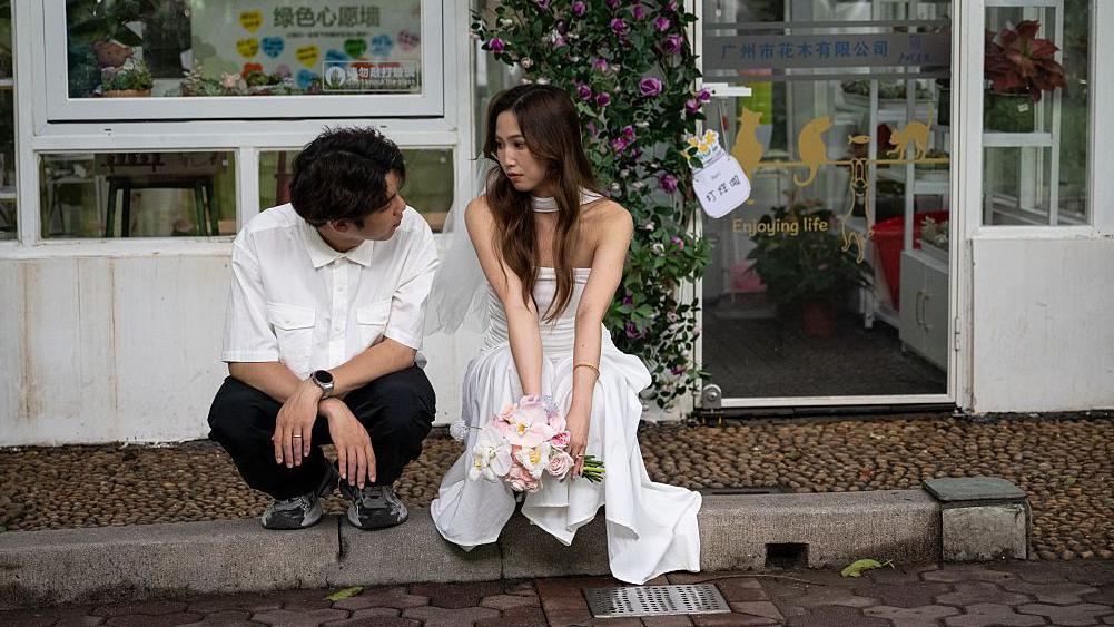 Par se fotografiše ispred Biroa za civilne poslove 20. maja 2025. godine u Guangdžouu, provincija Guangdong u Kini