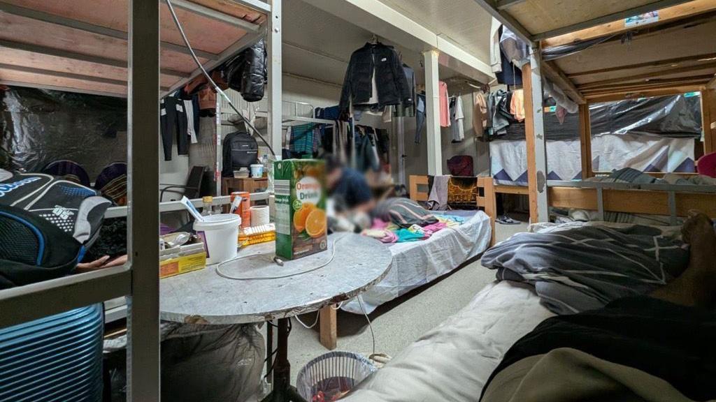 skromna baraka radnika u kojoj su krevet i razbacane stvari