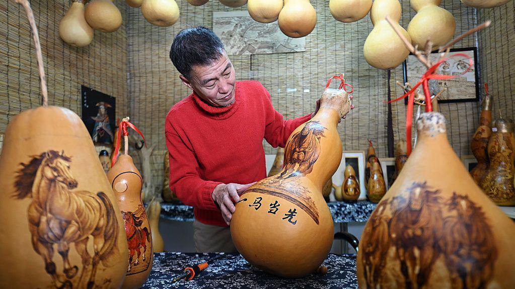 Čovek obučen u crveni džemper posmatra niz predmeta sa slikama konja.
