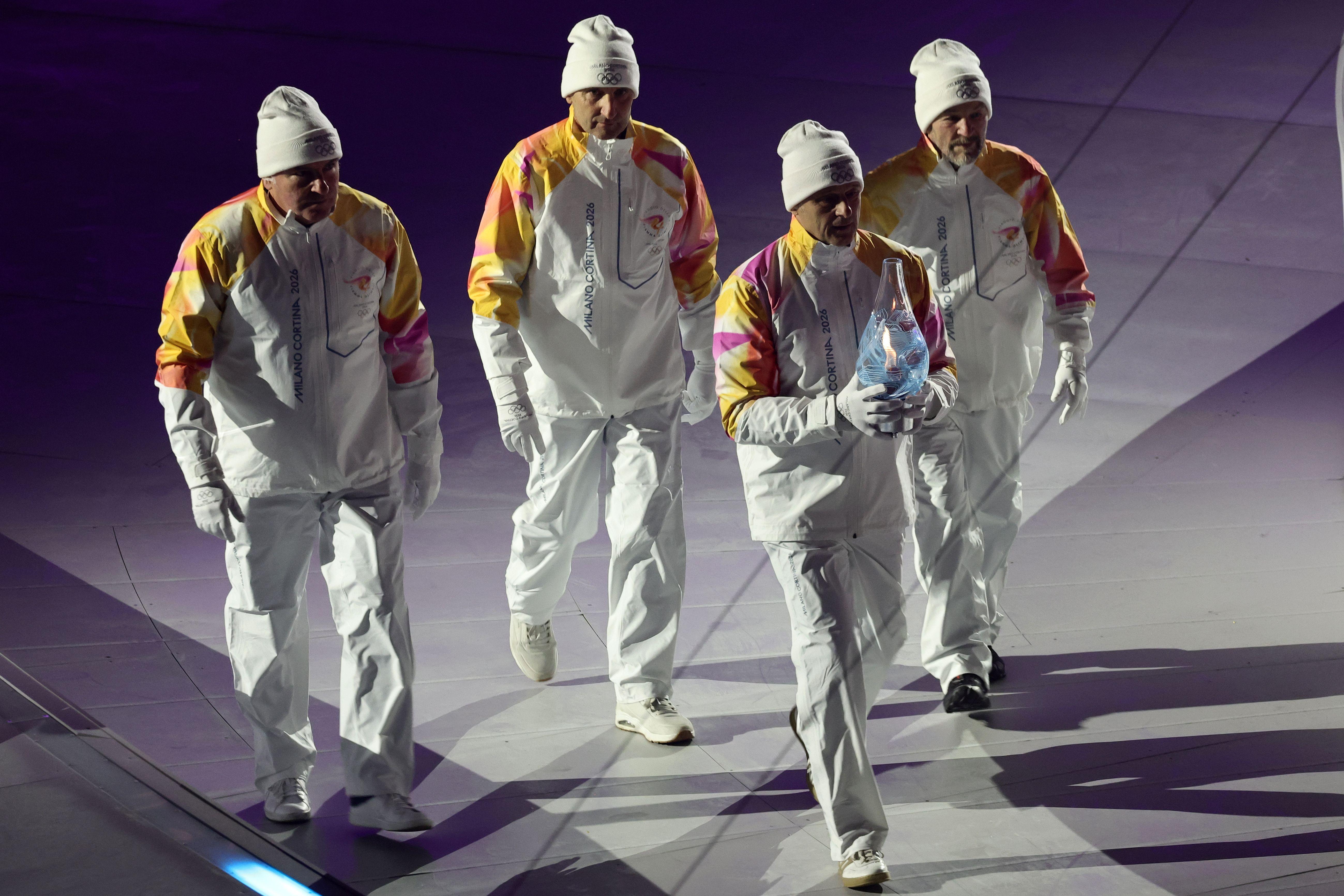 Zatvaranje Zimskih olimpijskih igara kroz fotografije 1 Četvorica muškaraca u belim odelima i sa belim kapama na glavama, olimpijski šampioni iz Lilehamera 1994. godine, u štafeti 4x10 km u skijaškom trčanju, nose olimpijski plamen