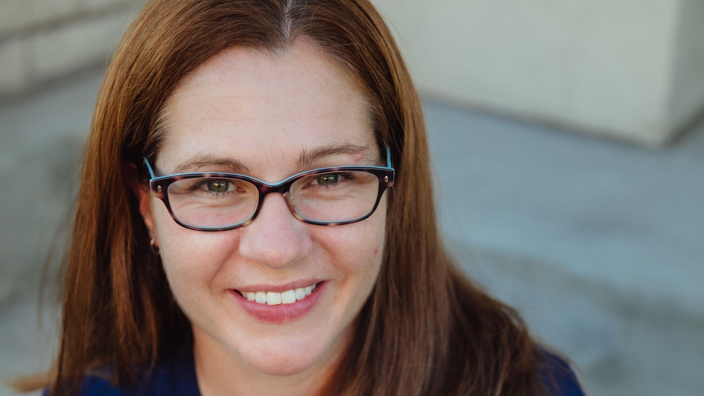 žena sa naočarima gleda u kameru i smeška se