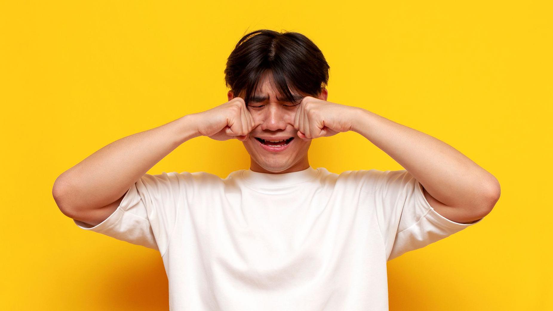 Čovek trlja oči dok plače