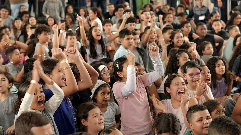 Students celebrate the award announcement in the school courtyard by cheering and raising their hands. They have big smiles on their faces and seem to be cheering.