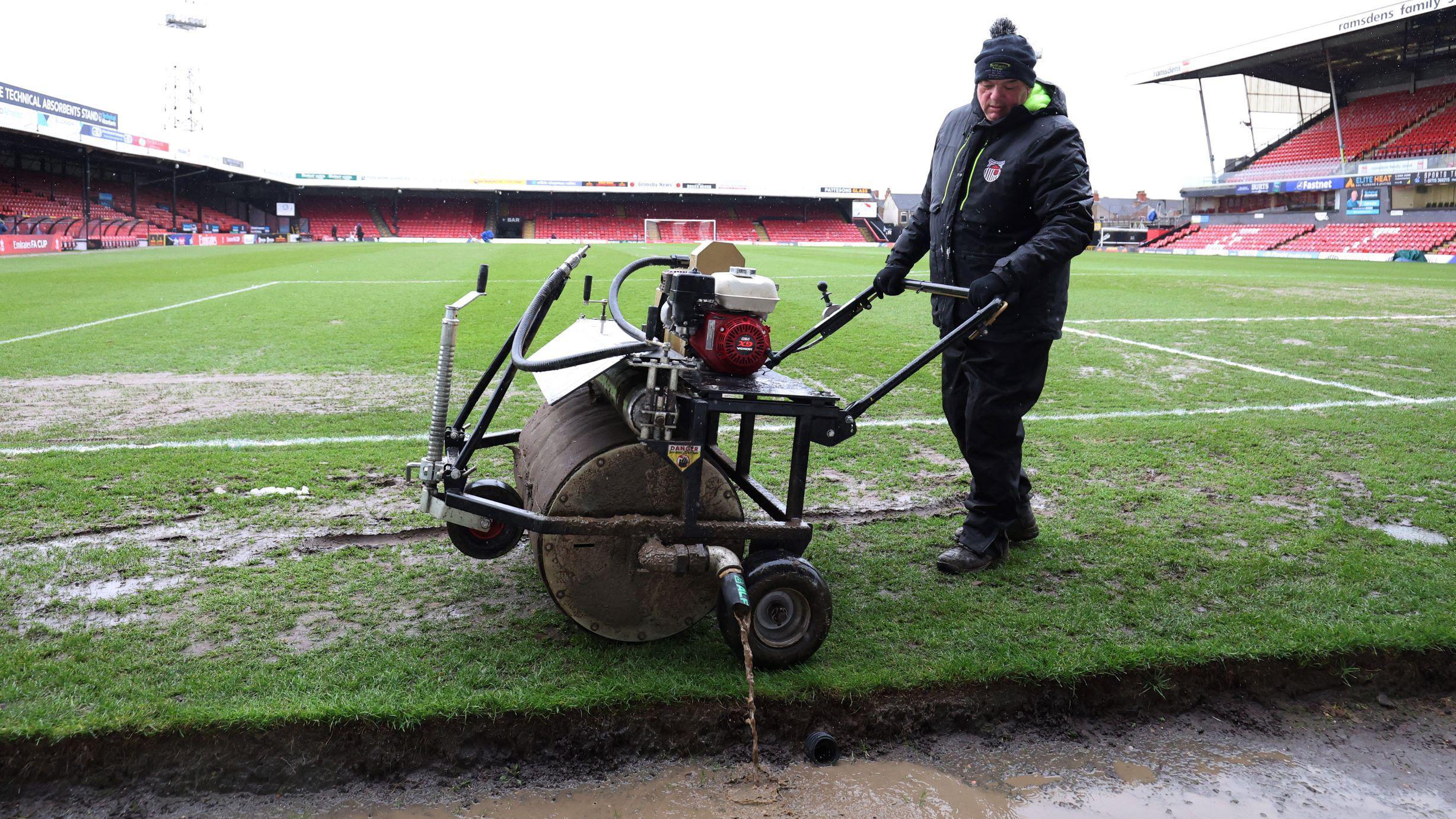 'Šmek prošlih vremena': Grimzbi i Vulfsi plesali po kaljuzi - u fotografijama 10 Pokušaji da se voda izbaci sa terena pred meč