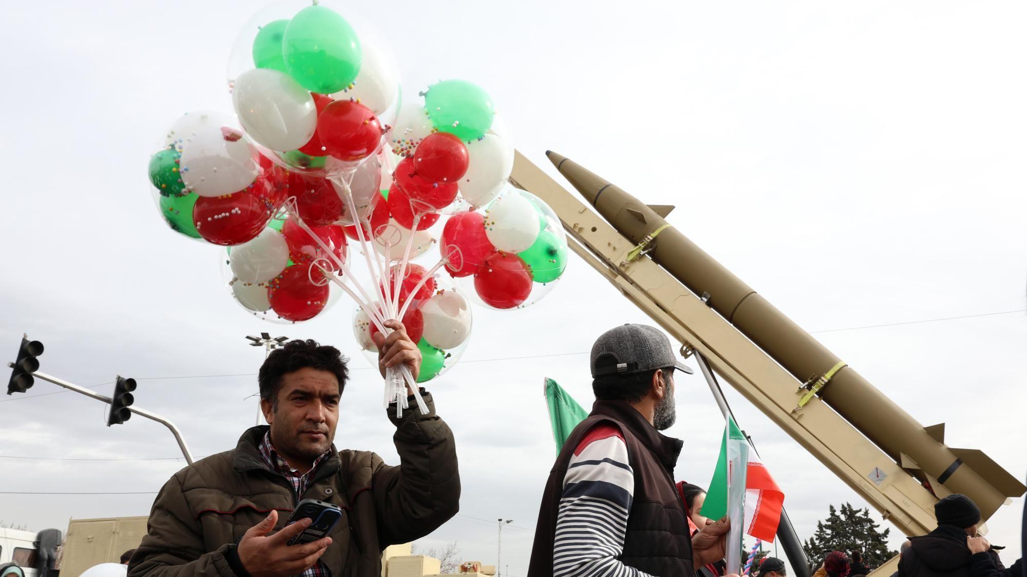 Iranac drži gomilu zelenih, crvenih i belih balona blizu balističke rakete tokom proslave 47. godišnjice Islamske revolucije u Teheranu, Iran (11. februar 2026.)