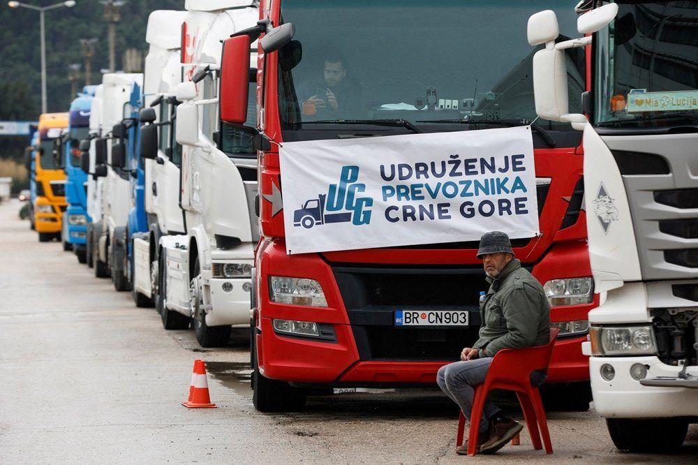 EU poručila kamiondžijama sa Balkana: 'Nema ustupaka' 4 kamiondžije, crnogorski kamioni, crnogorske kamiondžije, vozač kamiona sedi pored desetine vozila parkiranih ispred Luke Bar