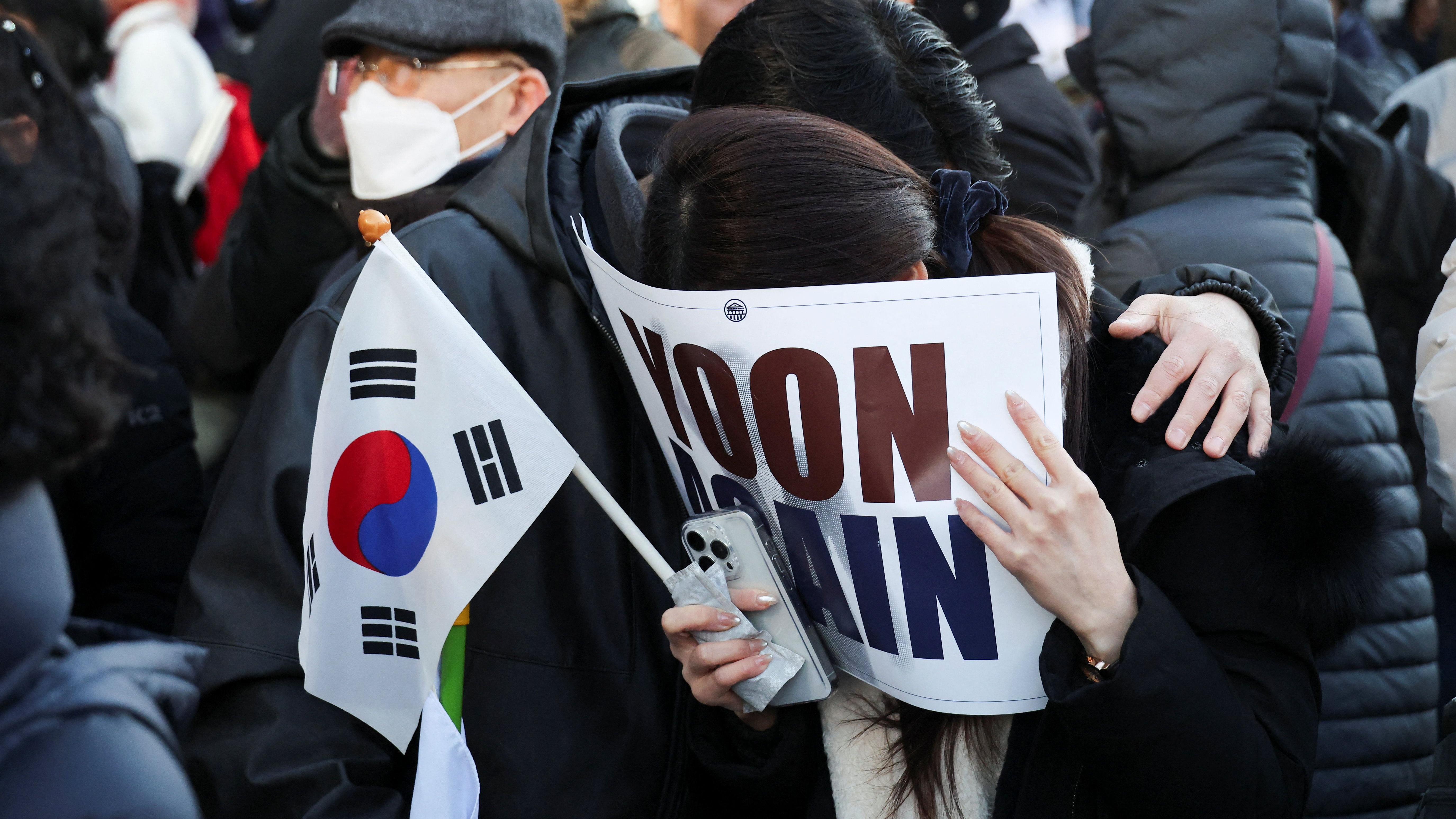 ljudi se kriju iza zastave i plaču 