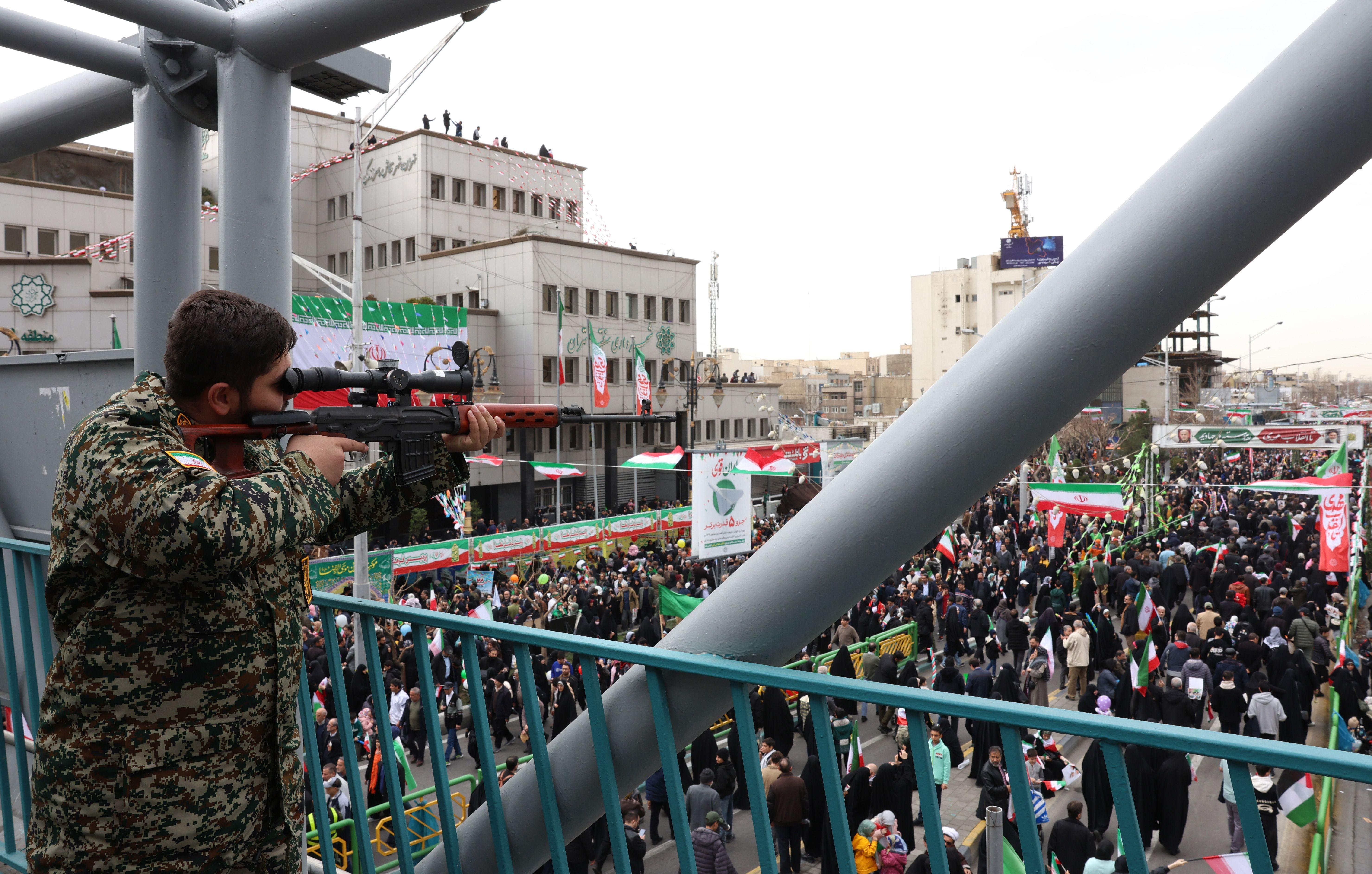 muškarac u maskirnoj uniformi sa snajperom nagleda proslavu 47. godine Islamske Republike Iran u Teheranu