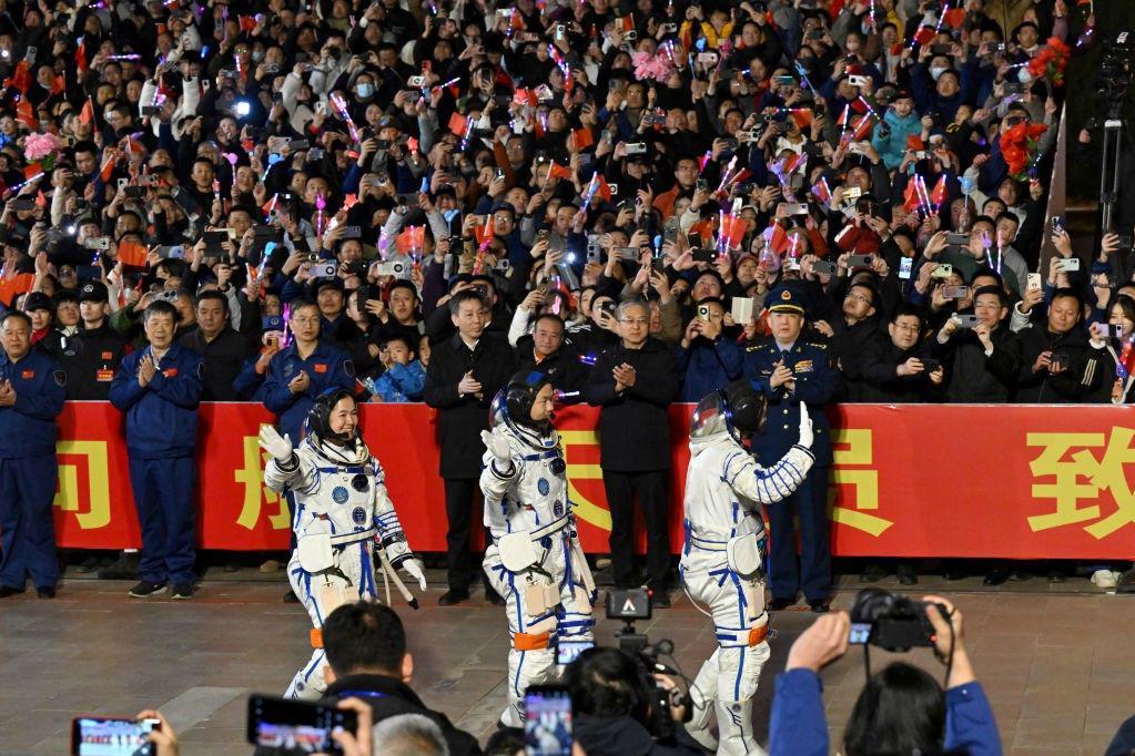 Tri kineska astronauta prolaze pored gomile ljudi koji mašu zastavama, kamerama i telefonima pred odlazak u svemir kako bi sproveli istraživanje na svemirskoj stanici Tjangong