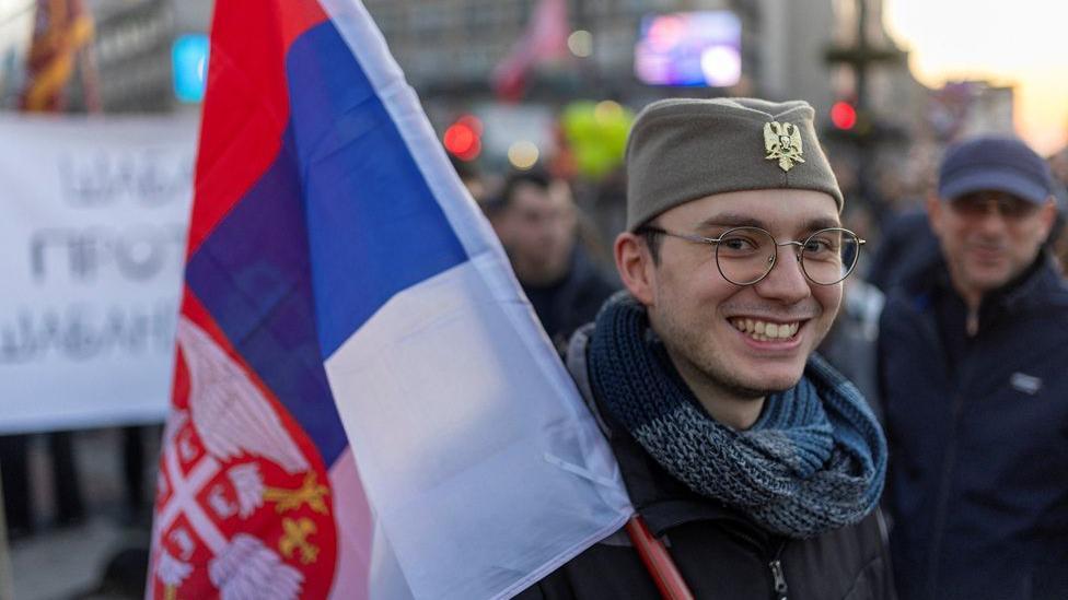 Lokalni izbori u Srbiji, 10 novih trka: Ko, gde, kada i kakva je uloga 'fantomskih lista' 1 momak sa šajkačom, drži zastavu Srbije na studentskom protestu